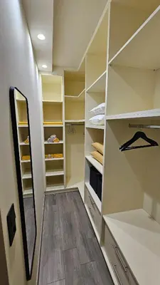 a walk in closet with white cabinets and a mirror at Her Luxury Apartment in Athens