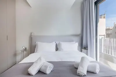 a white bedroom with a bed with towels on it at The HostMaster WiseView Azure in Athens