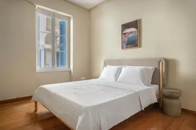 a bedroom with a bed with white sheets and a window at Grand Haven - New Renovated Spacious Apts in Prime Location in Athens