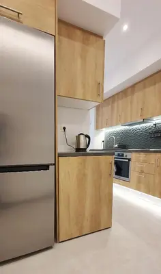 a kitchen with a stainless steel refrigerator and wooden cabinets at Condo, Hilton & Caravel area, Athens Center in Athens