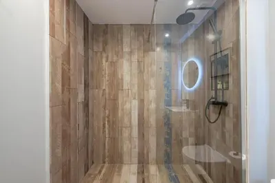 a bathroom with a shower with a wooden wall at Zen Rhea - Urban Spacious Loft in Athens Center in Athens