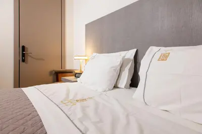 a white bed with white sheets and pillows at Hotiday Athens Acropolis in Athens