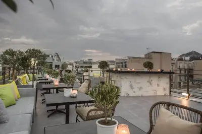 a rooftop patio with tables and chairs on a building at Hotiday Athens Acropolis in Athens