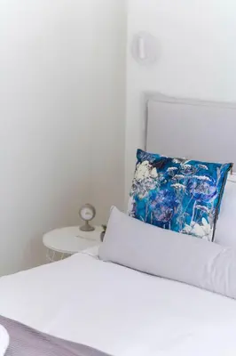 a white bed with a blue pillow on top of it at The HostMaster WiseView Panorama in Athens