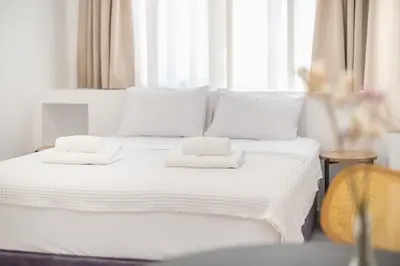 a white bed with two towels on top of it at Urban Couples Retreat With Rooftop Access - Zen Selene By Tessera in Athens