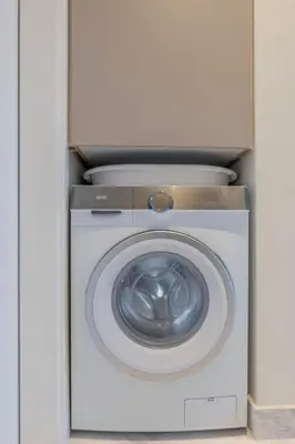 a white washing machine in a white cabinet at The HostMaster WiseView Celeste in Athens