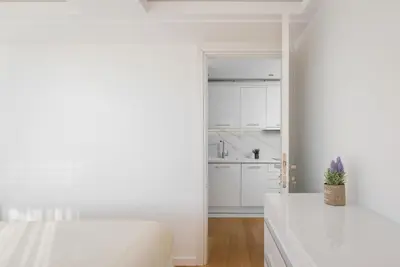 a white kitchen with white cabinets and a bed at Ellinikon 360 Roof Top in Athens