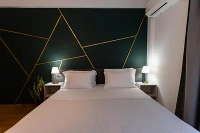 a bedroom with a large bed with a black and gold wall at Cozy Nest in Athens