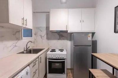 a white kitchen with a stove and a sink at Cozy Nest in Athens