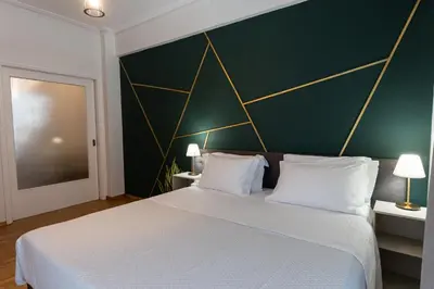 a bedroom with a large bed with a green wall at Cozy Nest in Athens