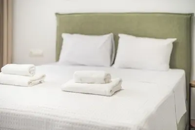 a white bed with two folded towels on it at Spacious Designed Studio City Center - Zen Metis By Tessera in Athens