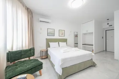 a bedroom with a white bed and a green chair at Spacious Designed Studio City Center - Zen Metis By Tessera in Athens