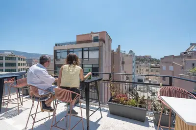 a man and a woman sitting at a table on a balcony at Bright & Airy Family Studio with Rooftop Access - Zen Theia by Tessera in Athens