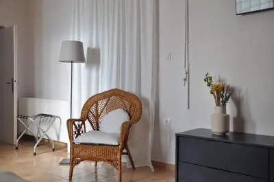 a wicker chair sitting in a room with a dresser at The BloomYard in Markopoulo