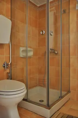 a bathroom with a toilet and a glass shower at The BloomYard in Markopoulo