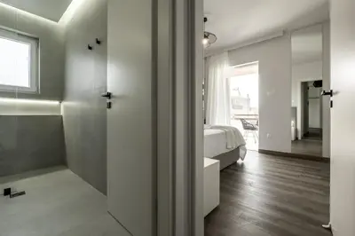 a bedroom with a bed and a bathroom with a shower at Glyfada Aelia Prestige in Athens