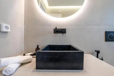 a bathroom with a black bath tub with a round mirror at Glyfada Aelia Prestige in Athens