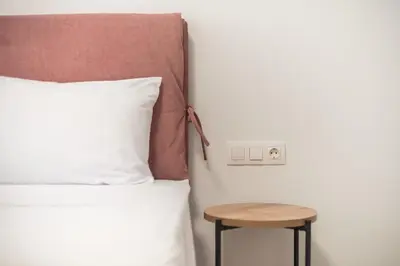 a bed with a wooden stool next to a bed with a pillow at Urban Getaway Cozy Open Space & Rooftop Lounge Zen Artemis By Tessera in Athens