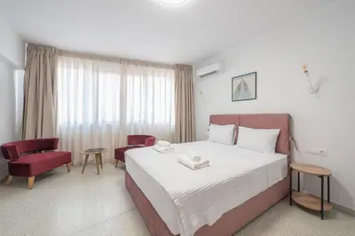 a bedroom with a large bed and a red chair at Urban Getaway Cozy Open Space & Rooftop Lounge Zen Artemis By Tessera in Athens