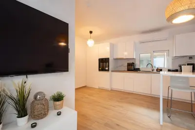 a kitchen with white cabinets and a large flat screen tv at The Secret Garden Stay in Athens