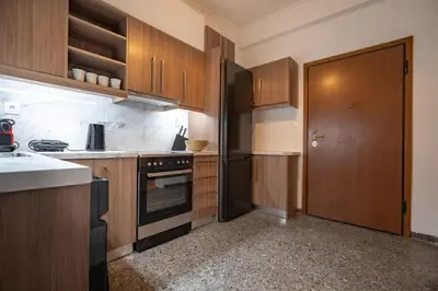 a kitchen with wooden cabinets and a black refrigerator at Clio 3BR apartment in Kypseli by ΜΡS in Athens