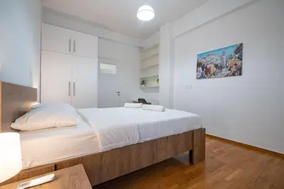 a bedroom with a large bed and a painting on the wall at Clio 3BR apartment in Kypseli by ΜΡS in Athens