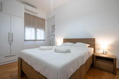 a white bedroom with a large bed with white sheets at Clio 3BR apartment in Kypseli by ΜΡS in Athens