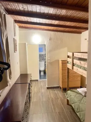 a room with a bed and a desk and a bathroom at The Simple Space, a pause near the sea in Ayía Paraskeví
