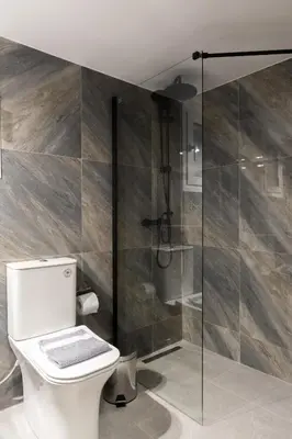 a bathroom with a toilet and a glass shower at Fresh 2 bdrm Apt in Koukaki in Athens