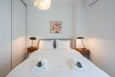 a bedroom with a large white bed with two lamps at 2BD Apt in Petralona Near Metro in Athens