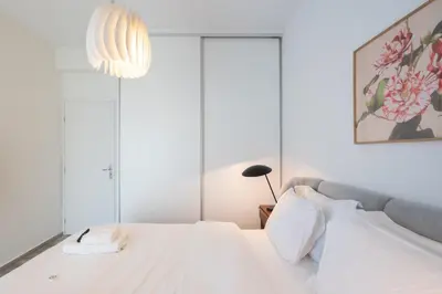 a bedroom with a white bed and a chandelier at 2BD Apt in Petralona Near Metro in Athens