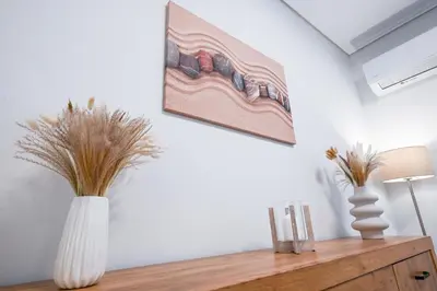 two white vases on a wooden dresser with a painting on the wall at Koukaki Modern Living in Athens