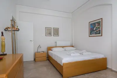 a bedroom with a bed with white sheets and a table at Spacious 3 Bedroom Apartment With Large Balcony in Athens