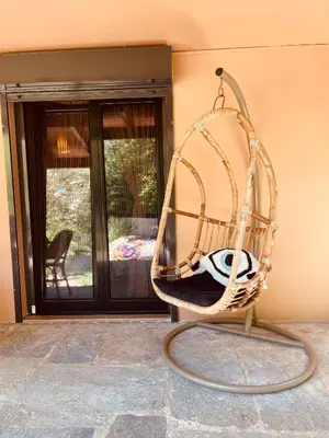 a wicker chair sitting in front of a house at Garden House 2 Bedroom Suite in Vari