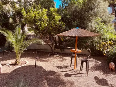 an umbrella and a chair and a table and stool at Garden House 2 Bedroom Suite in Vari