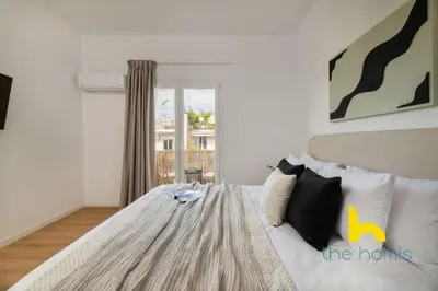 a white bedroom with a bed with a window at Modern Athens Stay - 2BR with Balcony, Steps to Metro in Athens