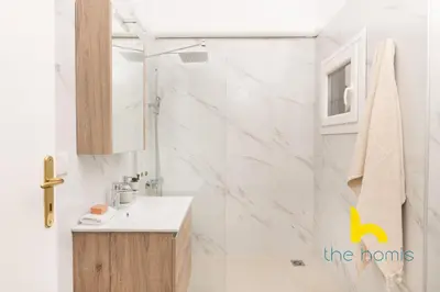a white bathroom with a sink and a shower at Modern Athens Stay - 2BR with Balcony, Steps to Metro in Athens