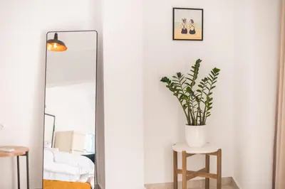 a mirror and a vase with a plant on a stool at Penthouse Zen Harmonia By Tessera in Athens