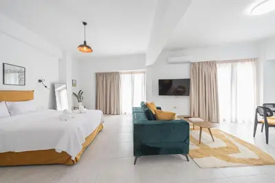 a white bedroom with a bed and a blue couch at Penthouse Zen Harmonia By Tessera in Athens
