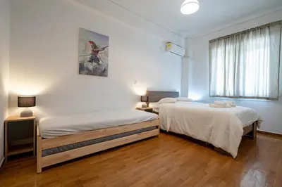 two beds in a room with white walls and wood floors at Phoebe 3BR apartment in Neos Kosmos by ΜΡS in Athens