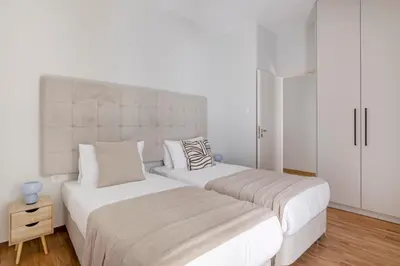 two beds in a bedroom with white walls and wood floors at Warm Athenian 2BR Apartment by Acropolis Hill by UPSTREET in Athens