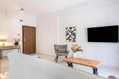 a living room with a couch and a tv on a wall at Warm Athenian 2BR Apartment by Acropolis Hill by UPSTREET in Athens
