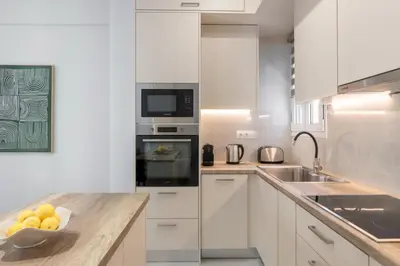 a white kitchen with a bowl of fruit on a counter at Warm Athenian 2BR Apartment by Acropolis Hill by UPSTREET in Athens