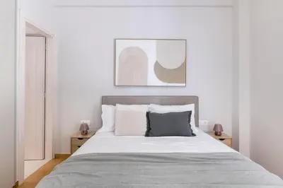 a bedroom with a large bed with white walls at Warm Athenian 2BR Apartment by Acropolis Hill by UPSTREET in Athens