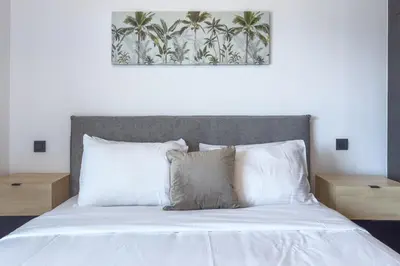 a bed with white pillows and a picture of palm trees at Phaedrus Living Apollo Skyview Penthouse in Athens