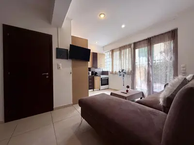 a living room with a couch and a kitchen at Alimos Cozy Apartment in Athens