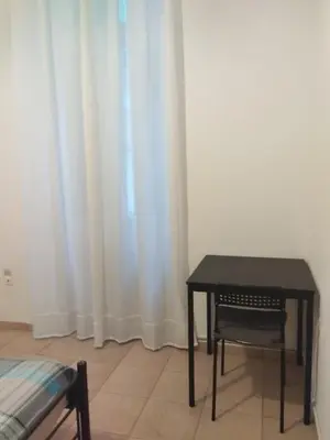 a table and a chair in a room with white curtains at Golden room 1 in Athens