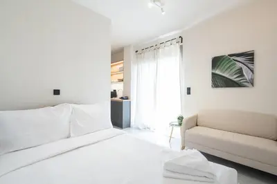 a white bedroom with a bed and a couch at LIV - Comfortable Athens Studios in Athens