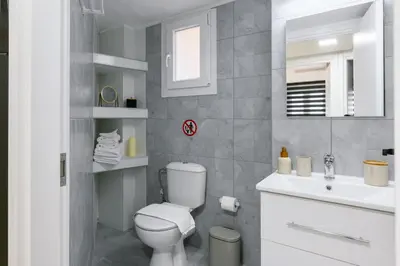 a white bathroom with a toilet and a sink at Elegant Urban Stay in Piraeus in Piraeus