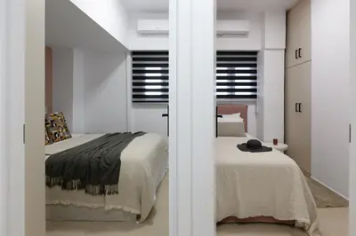 a bedroom with two beds and two windows at Elegant Urban Stay in Piraeus in Piraeus